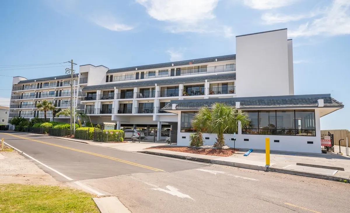 The building’s facade is framed by palm trees and the entrance area, suggesting a secure, inviting arrival experience. The welcoming mood highlights the transition from outside adventures to the comfort and safety offered onsite.